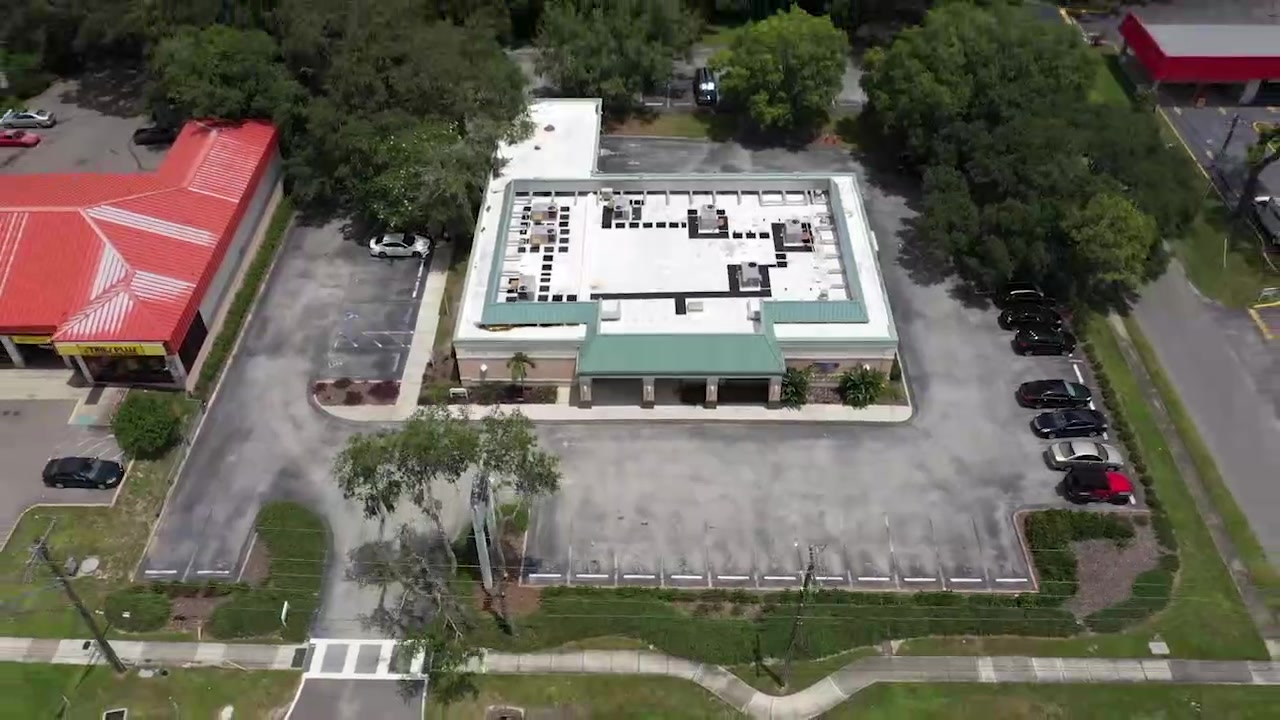 Aerial view of a commercial building, parking lot, sidewalks, and access driveways